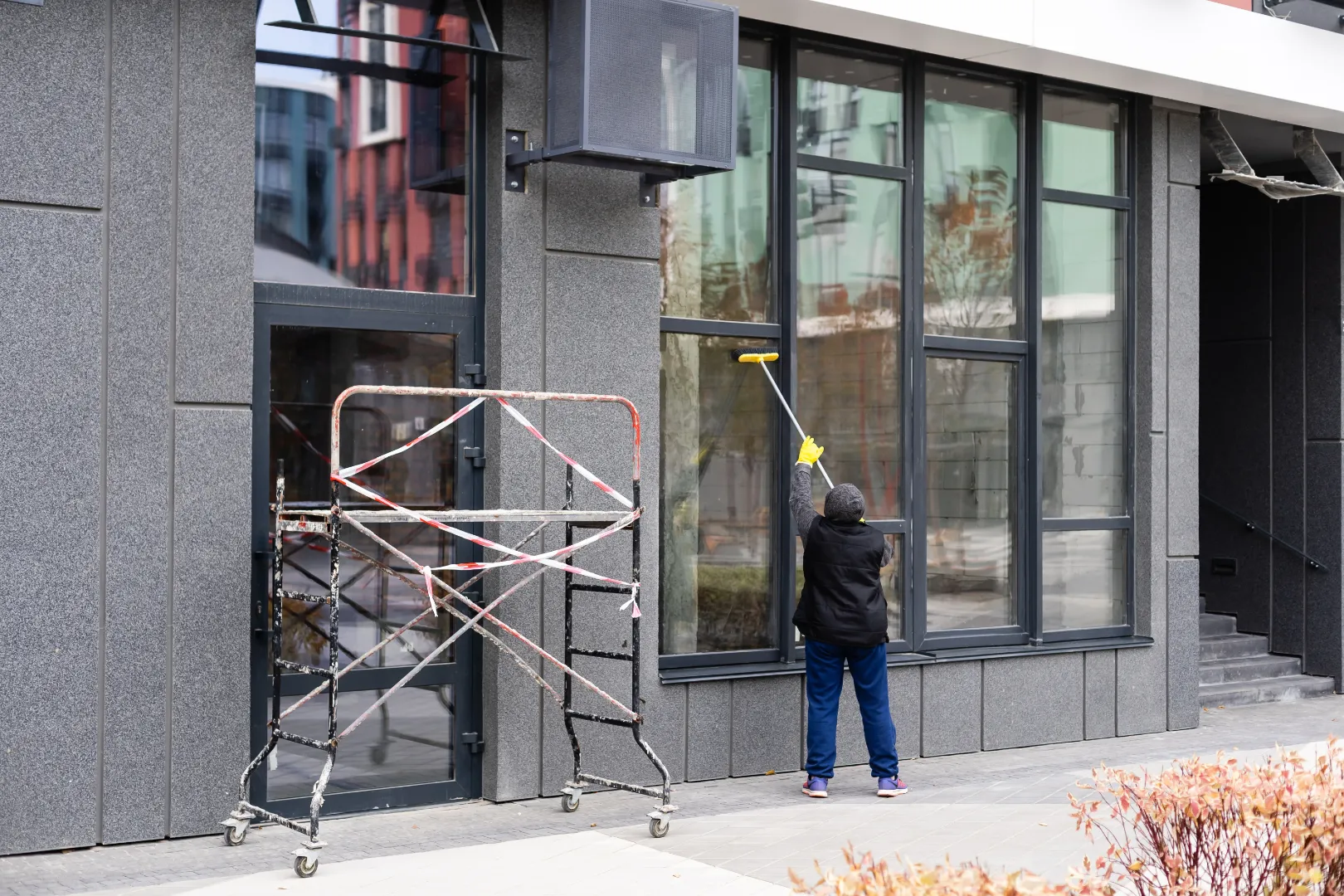 Professional cleaner washing windows at a commercial storefront
