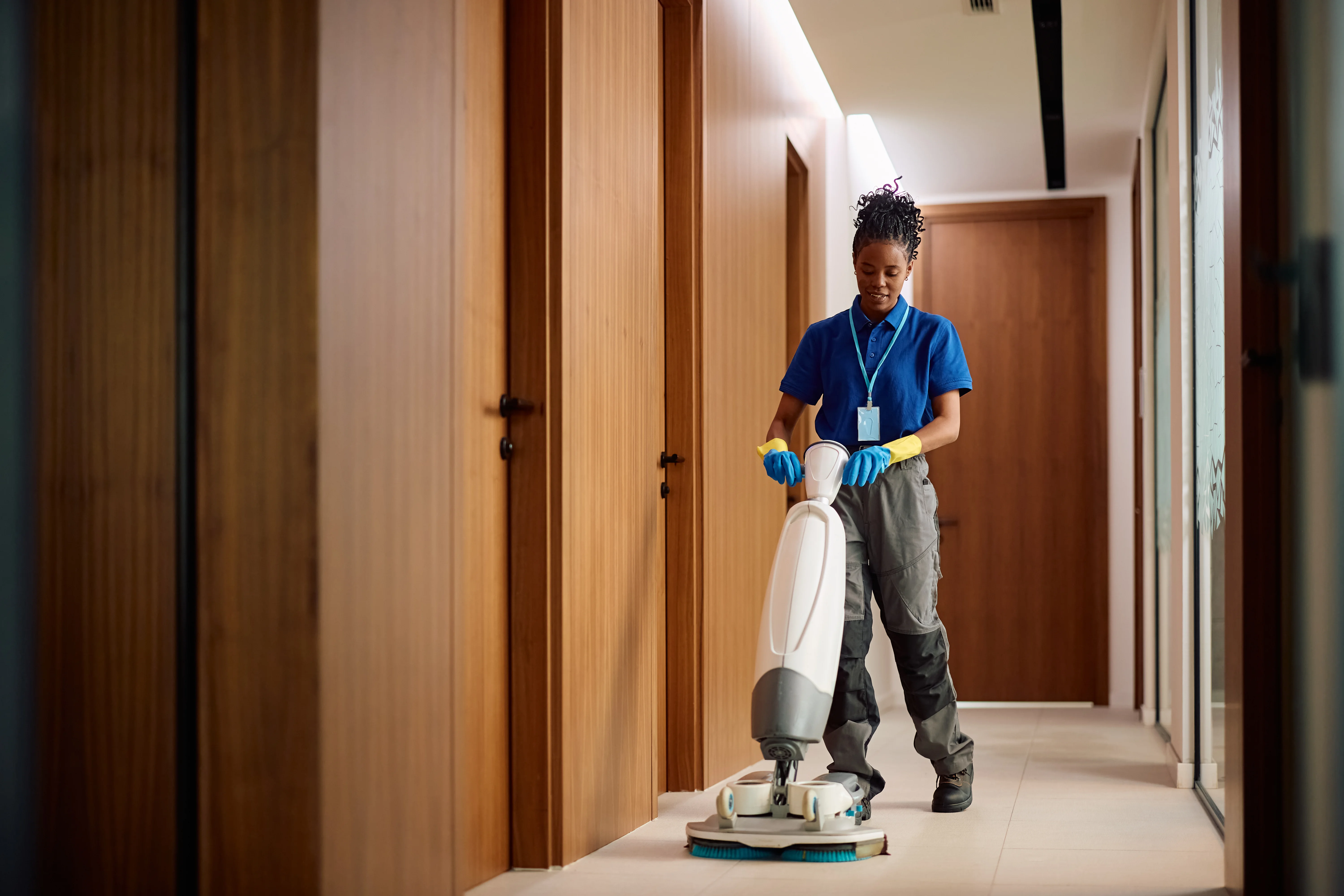 Commercial cleaner using a floor scrubber in a business hallway