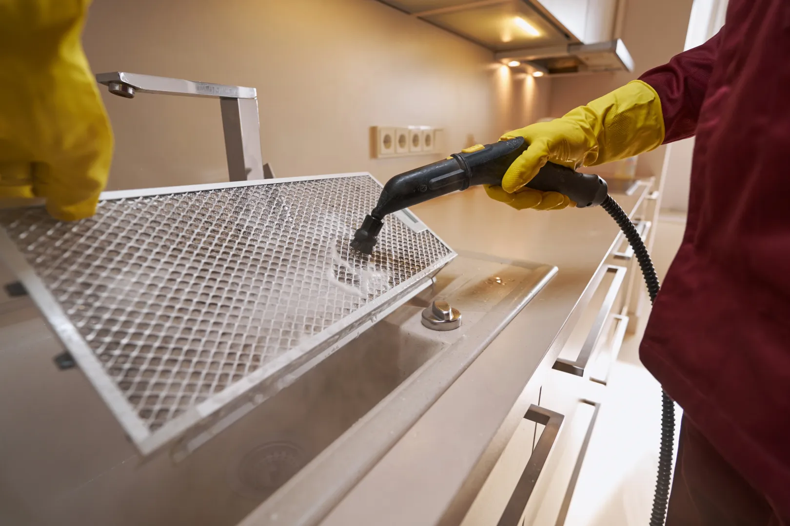 A cleaner using a steam cleaner to clean a kitchen machine part