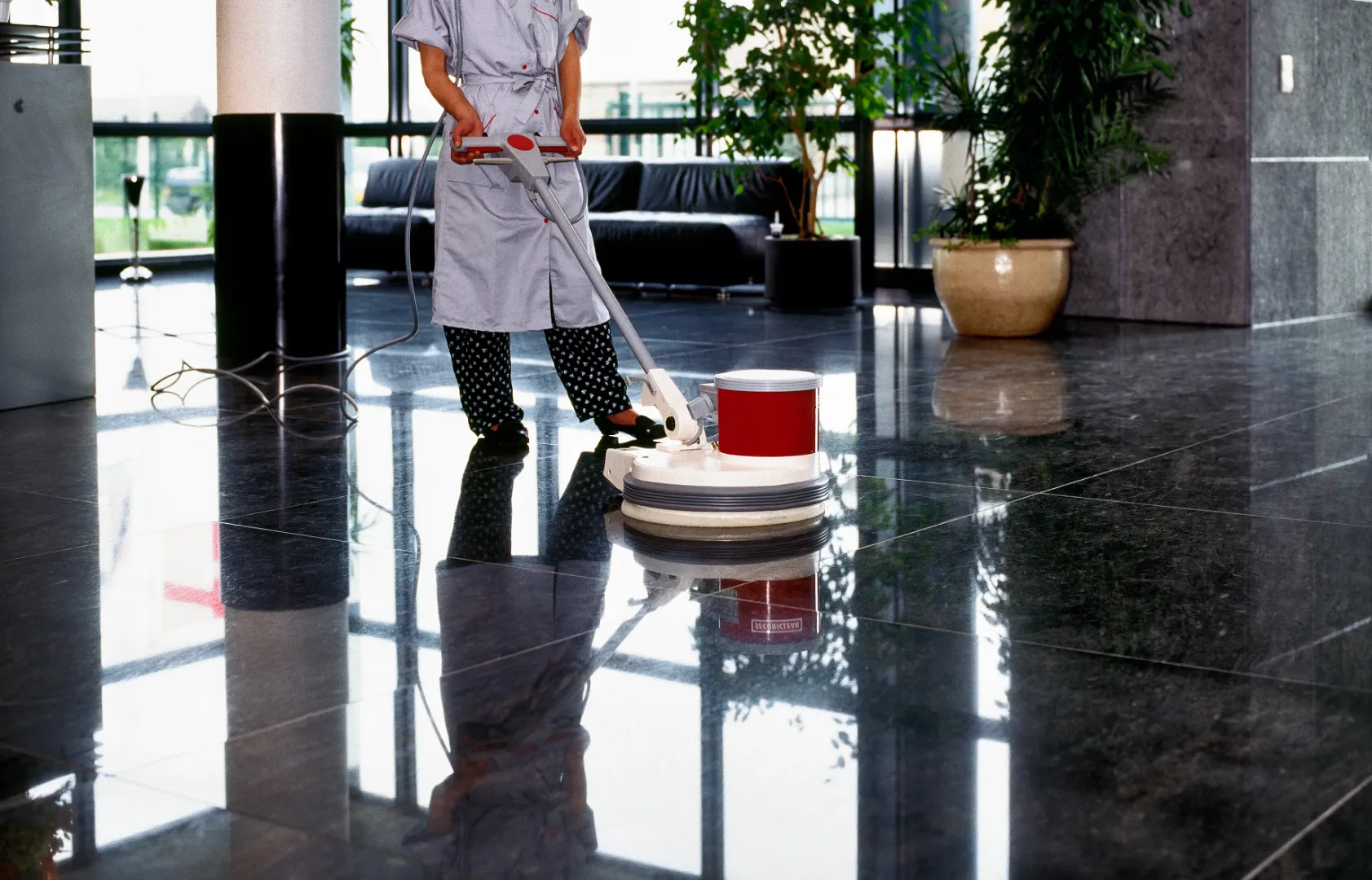 A man cleaning a polished floor with a floor scrubber