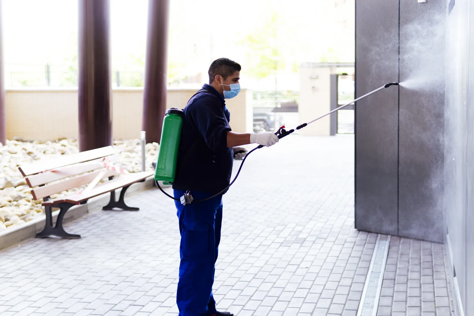 Worker using a sprayer to clean a commercial building