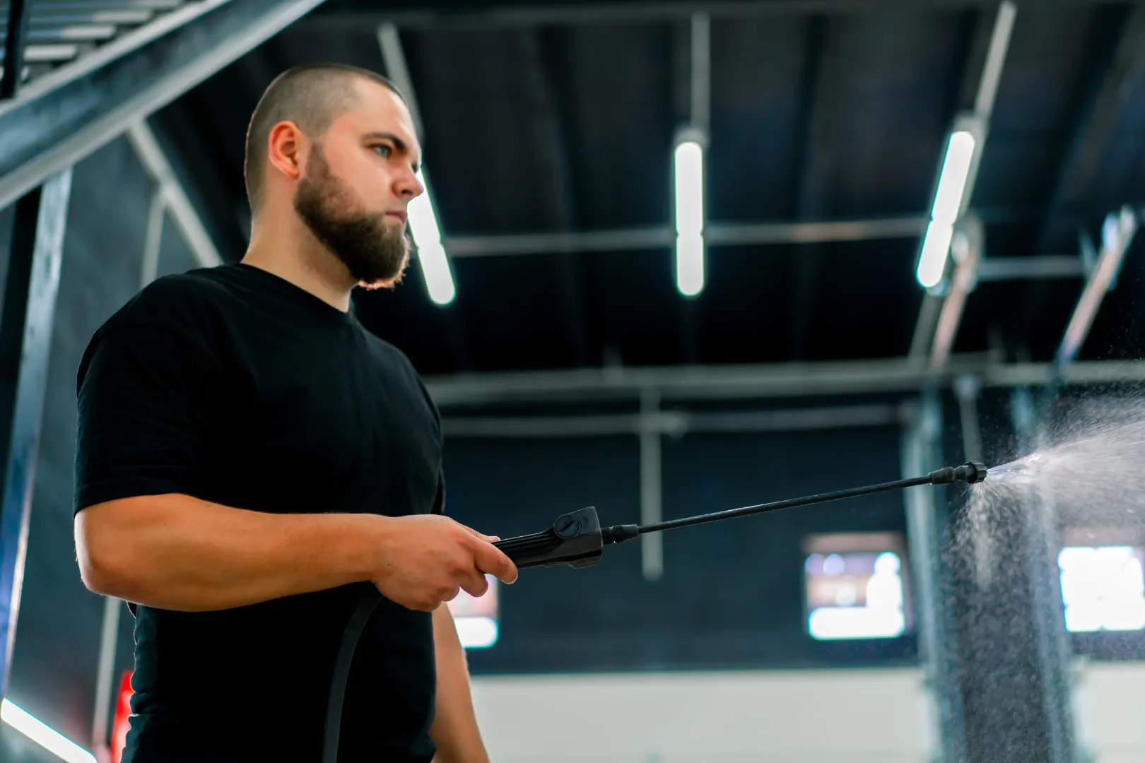 Worker using an electrostatic sprayer to clean gym equipment