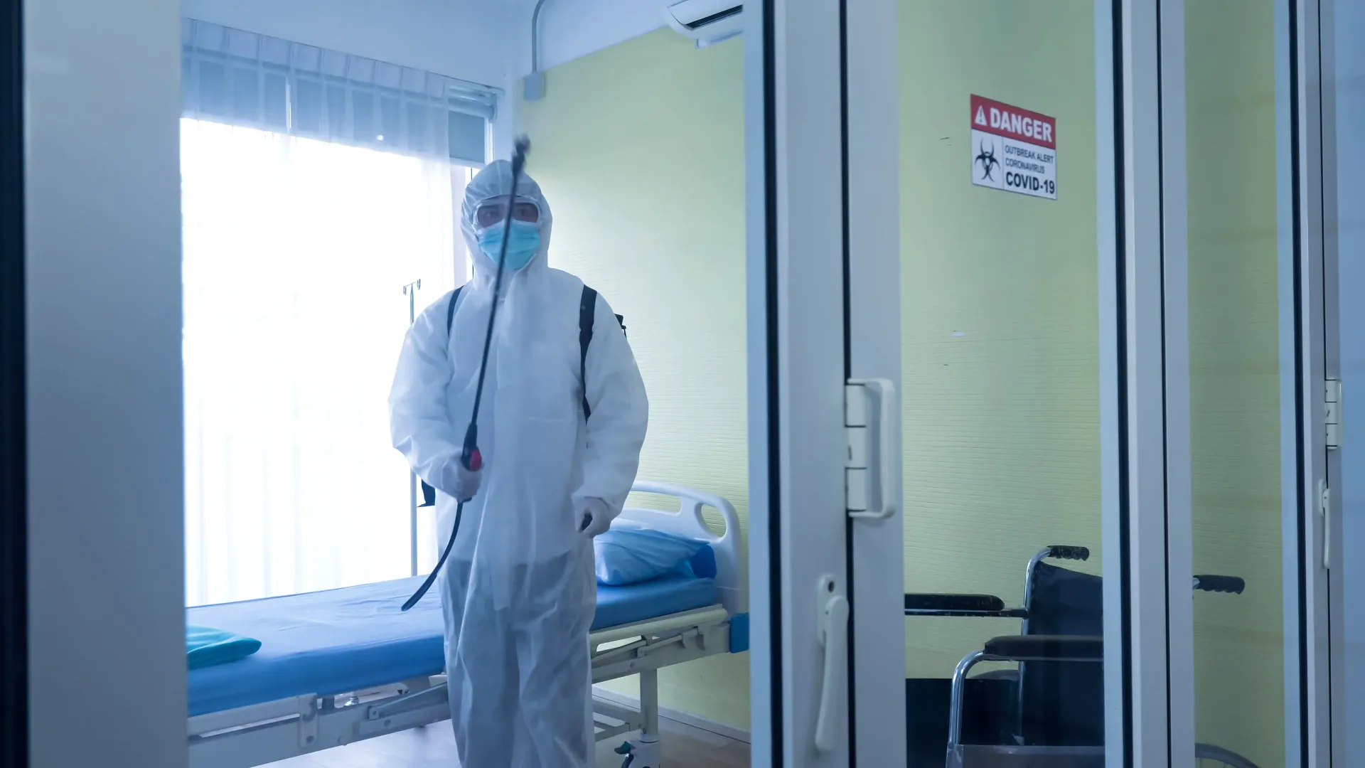 Worker using an electrostatic sprayer in a healthcare facility