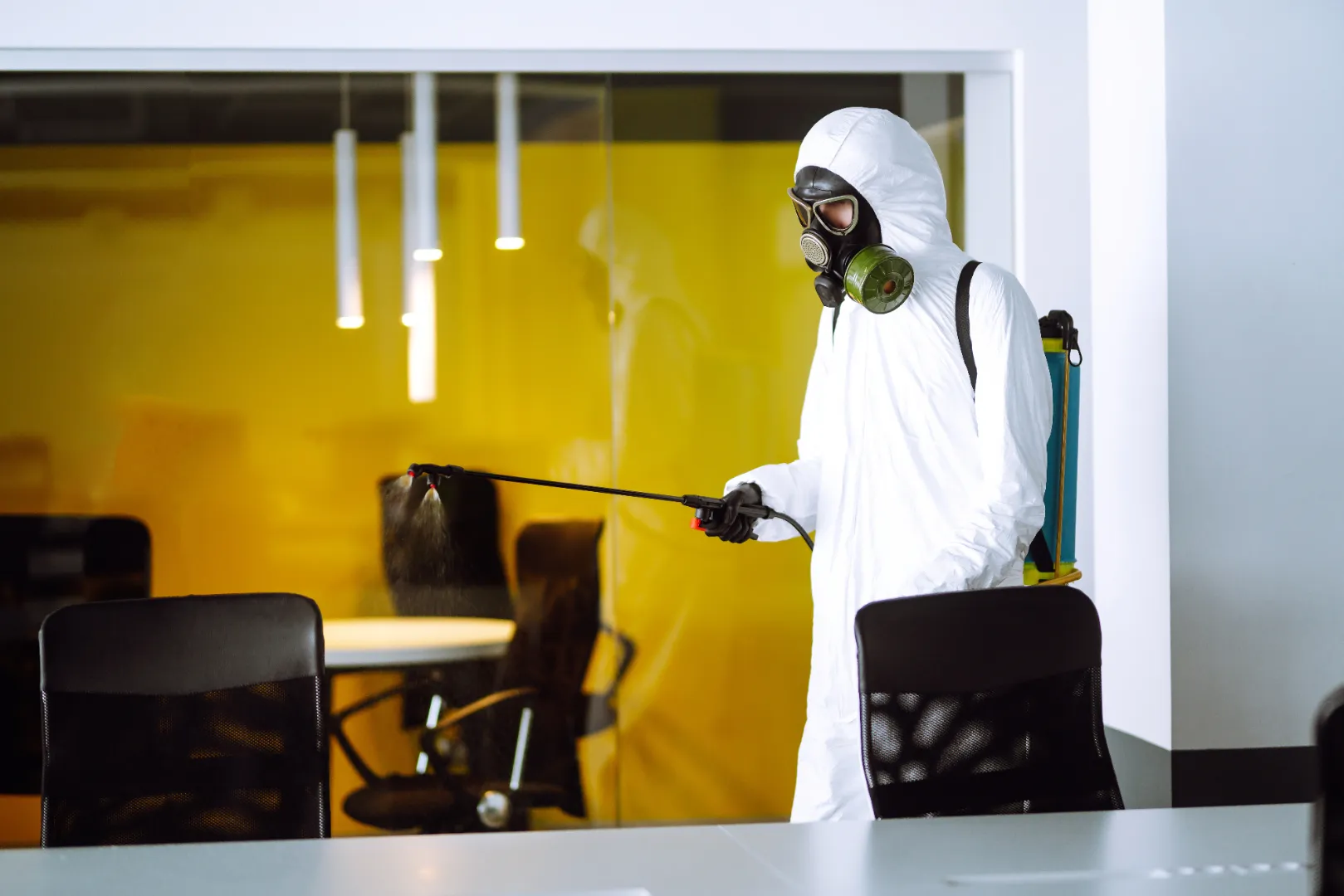 Worker using an electrostatic sprayer to clean an office