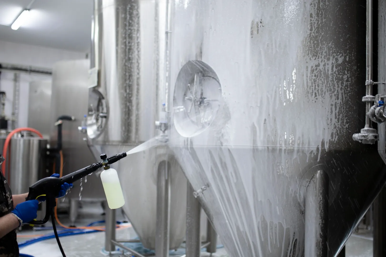 Worker pressure washing industrial machinery
