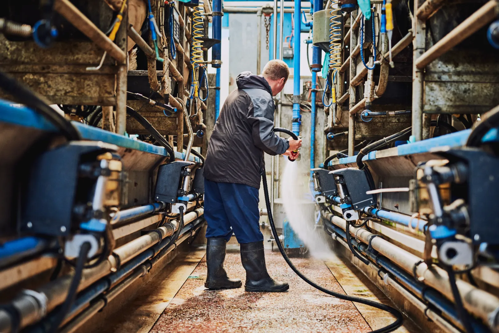 Worker pressure washing equipment in an industrial facility